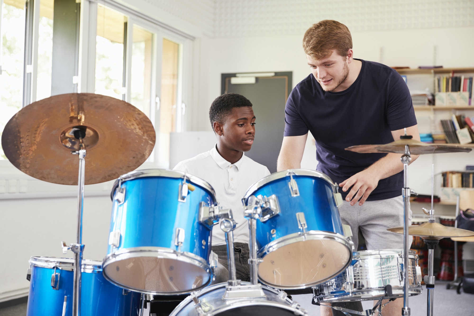 male-pupil-with-teacher-playing-drums-in-music-lesson.jpg